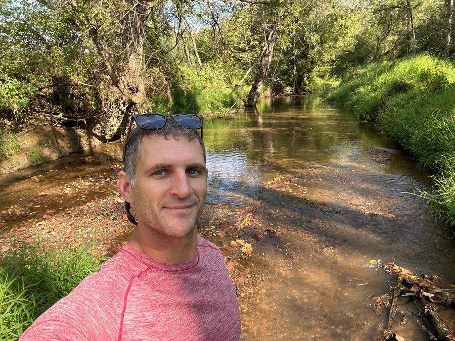 Tyler by a shallow creek in the Virginia countryside on a bright early-autumn day